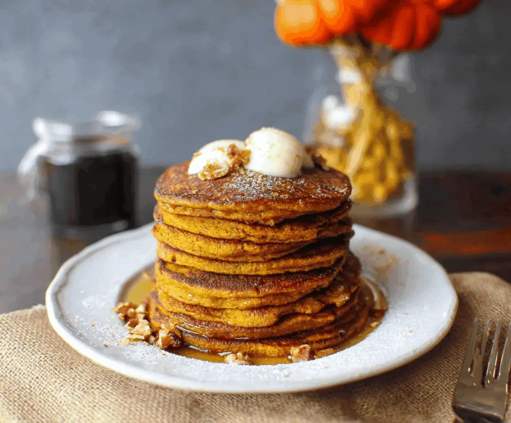 Delicious fluffy coconut flour pumpkin pancakes topped with maple syrup and fresh berries on a white plate, perfect for a healthy breakfast