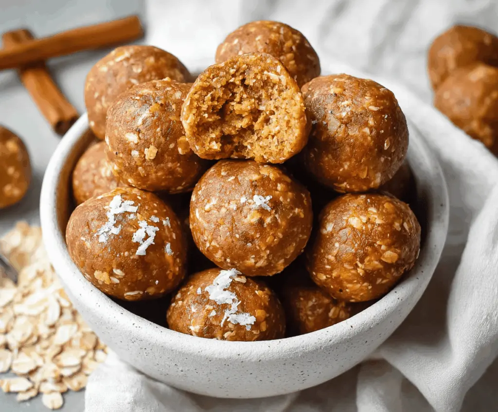 Healthy pumpkin spice protein balls on a white plate with cinnamon and pumpkin seeds, perfect for a nutritious snack.