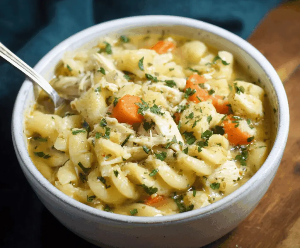 Creamy Parmesan Chicken Noodle Soup in a bowl with tender chicken, vegetables, and melted cheese, perfect for comforting meals.