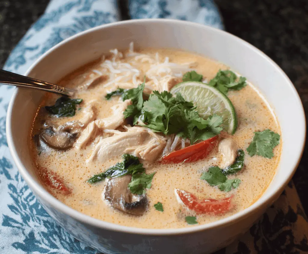 Creamy Thai Coconut Chicken Soup (Tom Kha Gai) with tender chicken, fragrant herbs, and fresh lime in a vibrant bowl