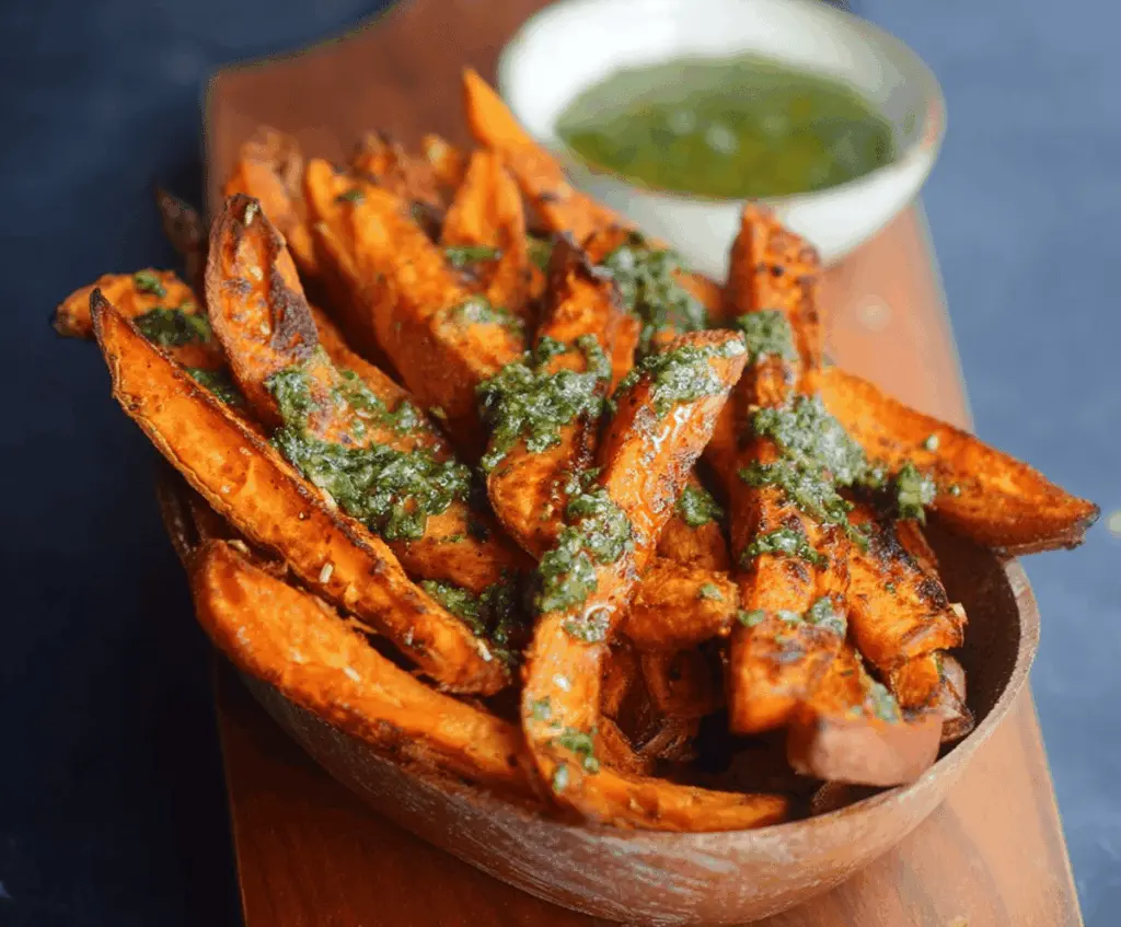 Delicious homemade pesto sweet potato fries served on a plate, crispy and garnished with fresh herbs, perfect for a healthy snack or side dish.