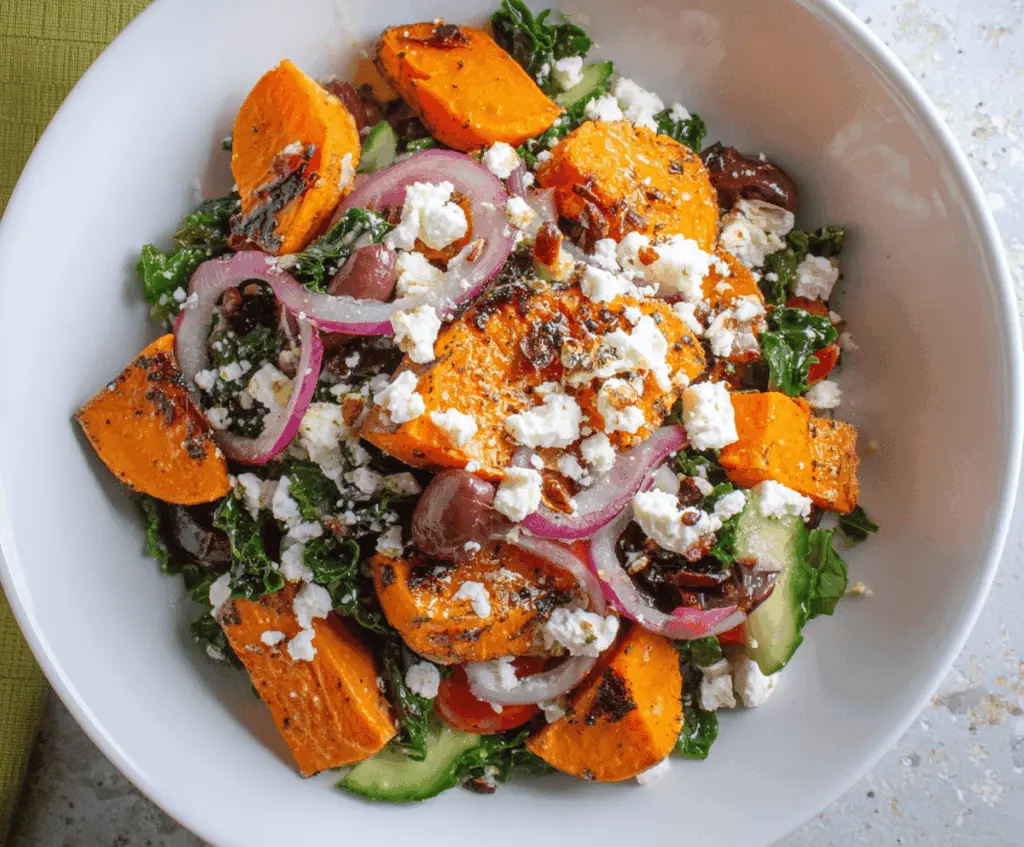 Colorful sweet potato Greek salad with fresh vegetables, feta cheese, and herbs in a bowl, perfect for a healthy meal.