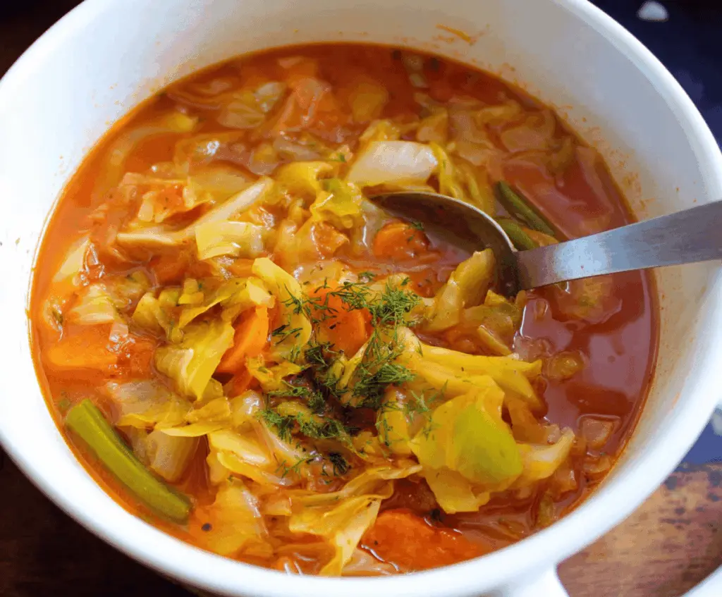 Healthy Weight Watchers Cabbage Soup in a bowl with fresh vegetables and herbs, perfect for a low-calorie diet meal
