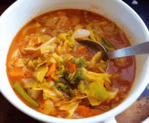 Healthy Weight Watchers Cabbage Soup in a bowl with fresh vegetables and herbs, perfect for a low-calorie diet meal