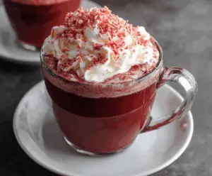 Rich and creamy red velvet hot chocolate topped with whipped cream and chocolate shavings.