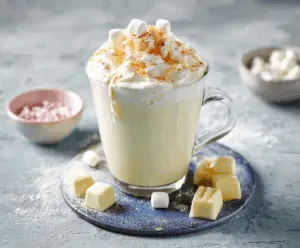 Creamy white hot chocolate in a mug topped with whipped cream and marshmallows.