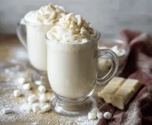Creamy white hot chocolate topped with whipped cream and marshmallows in a cozy mug
