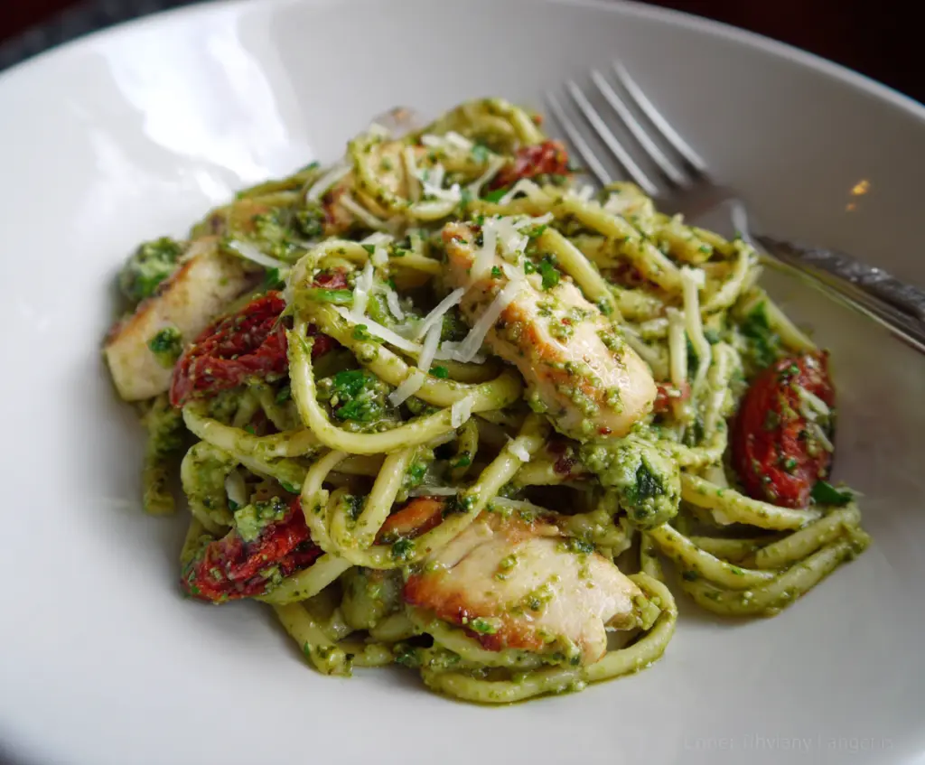 Delicious Cilantro Chicken and Pesto Pasta dish garnished with fresh herbs on a plate.