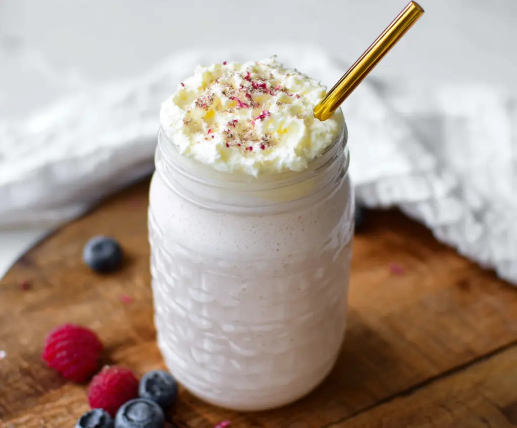 Healthy cottage cheese protein shake in a glass with fresh fruit on a kitchen counter.