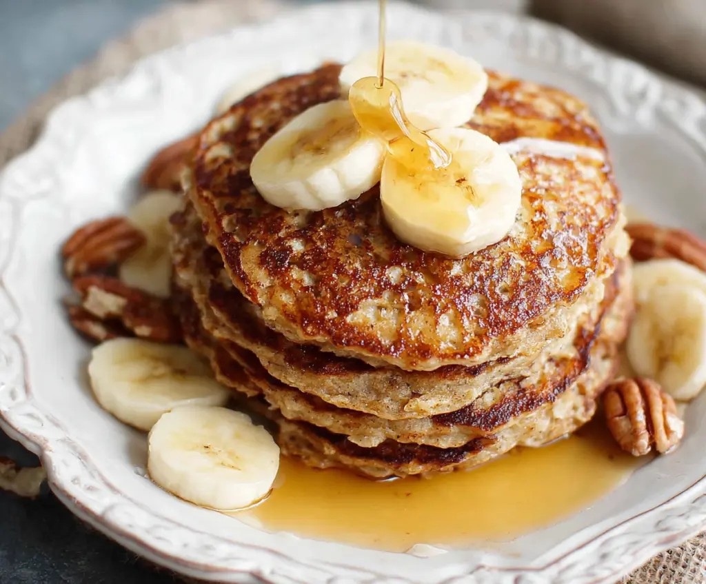 Delicious homemade banana oatmeal pancakes served on a plate with fresh fruit.