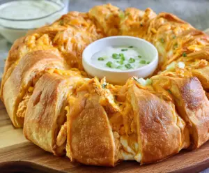 Delicious Buffalo Chicken Crescent Ring served on a white platter, garnished with fresh herbs.
