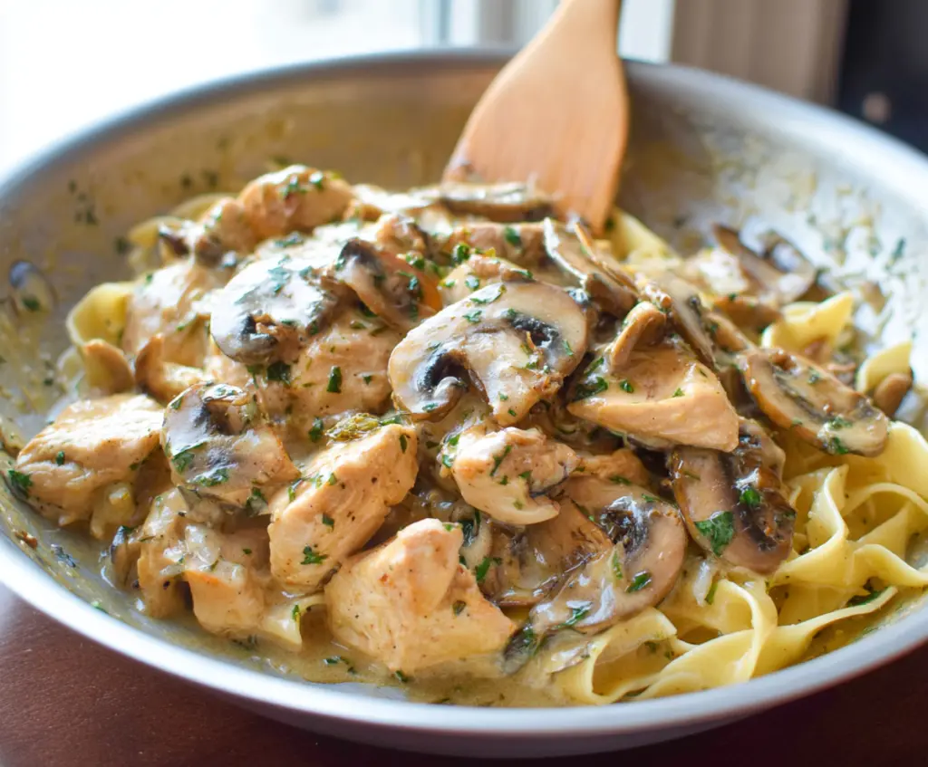 Delicious Chicken Mushroom Pasta served on a white plate with fresh herbs.
