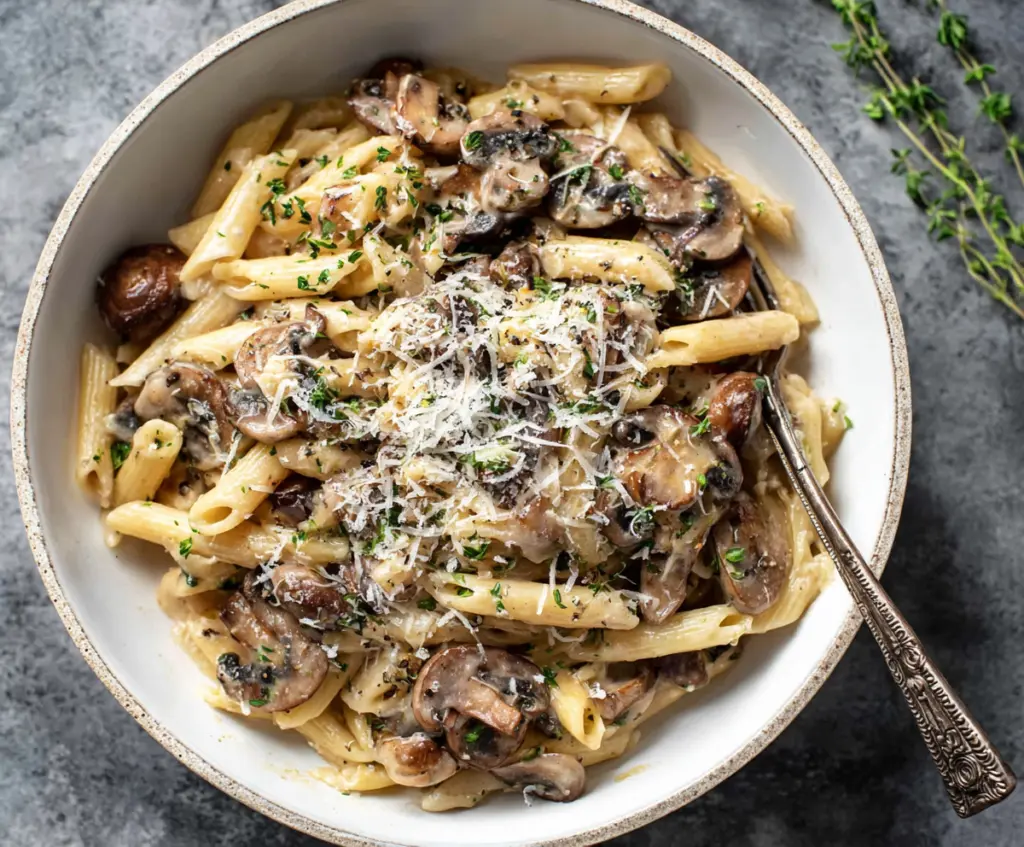 Creamy mushroom pasta with rich sauce served on a plate, garnished with herbs