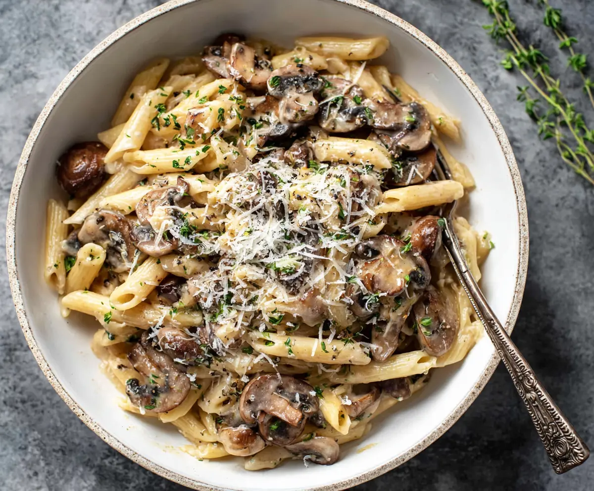 Creamy mushroom pasta with rich sauce served on a plate, garnished with herbs