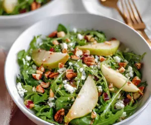 Fresh arugula and ripe pear salad with nuts and feta cheese on a plate, healthy and flavorful appetizer.