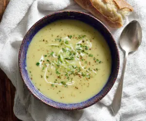 Creamy crockpot potato leek soup served in a bowl, garnished with fresh herbs.