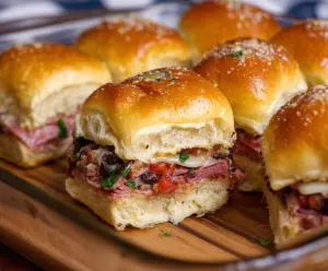 Delicious Muffuletta Sliders with layers of Italian meats, cheeses, and olive salad on mini buns.