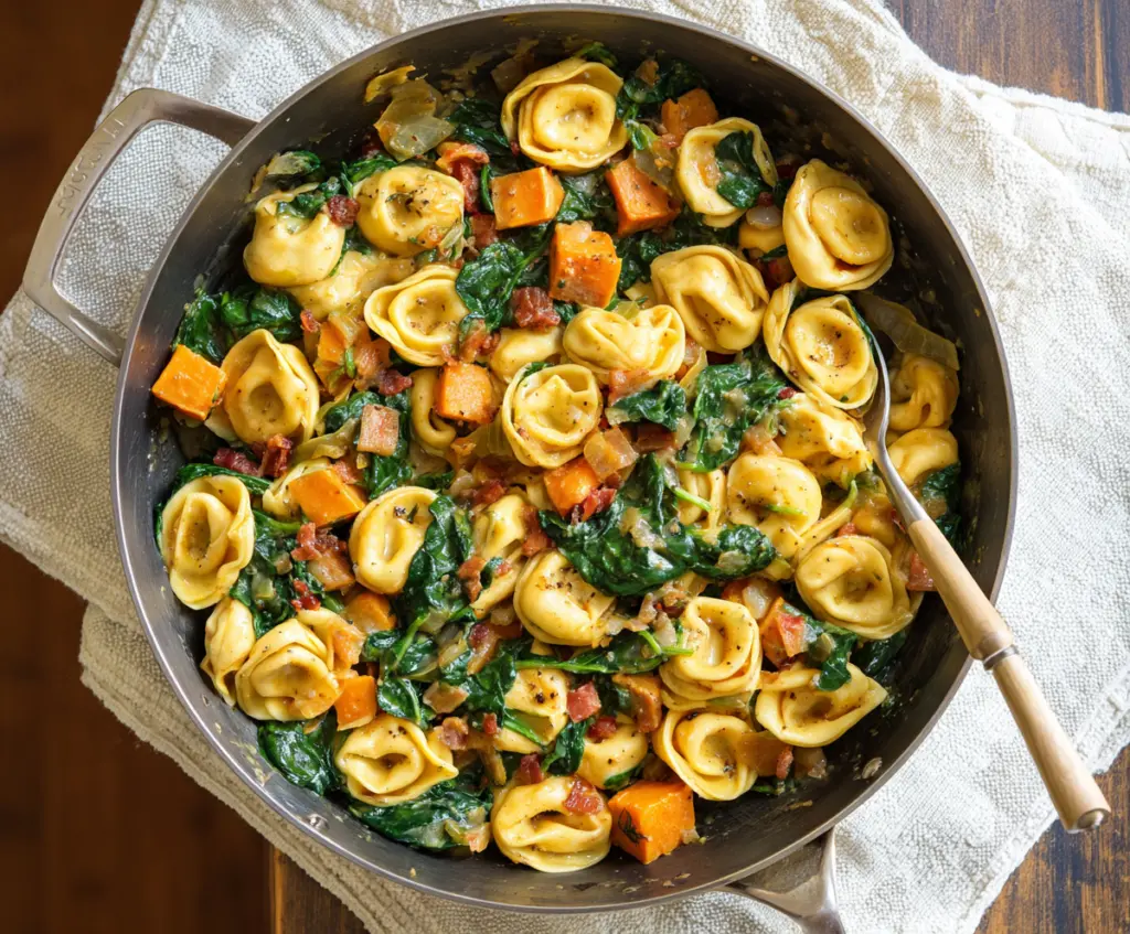 Delicious skillet tortellini with sweet potatoes and fresh spinach served in a rustic skillet.