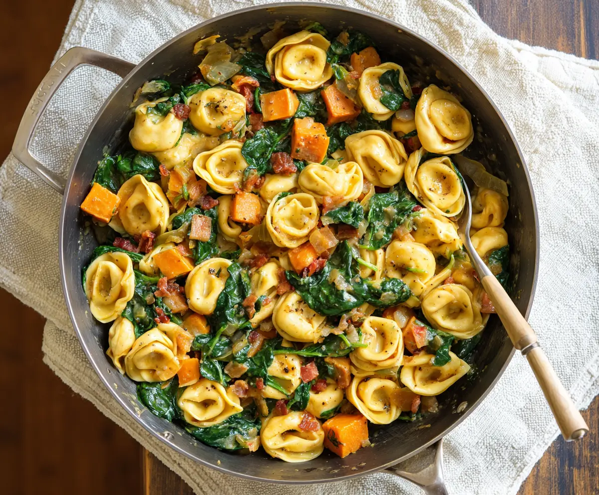 Delicious skillet tortellini with sweet potatoes and fresh spinach served in a rustic skillet.
