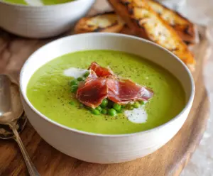 Creamy spring pea soup garnished with crispy prosciutto slices for a fresh, savory appetizer.