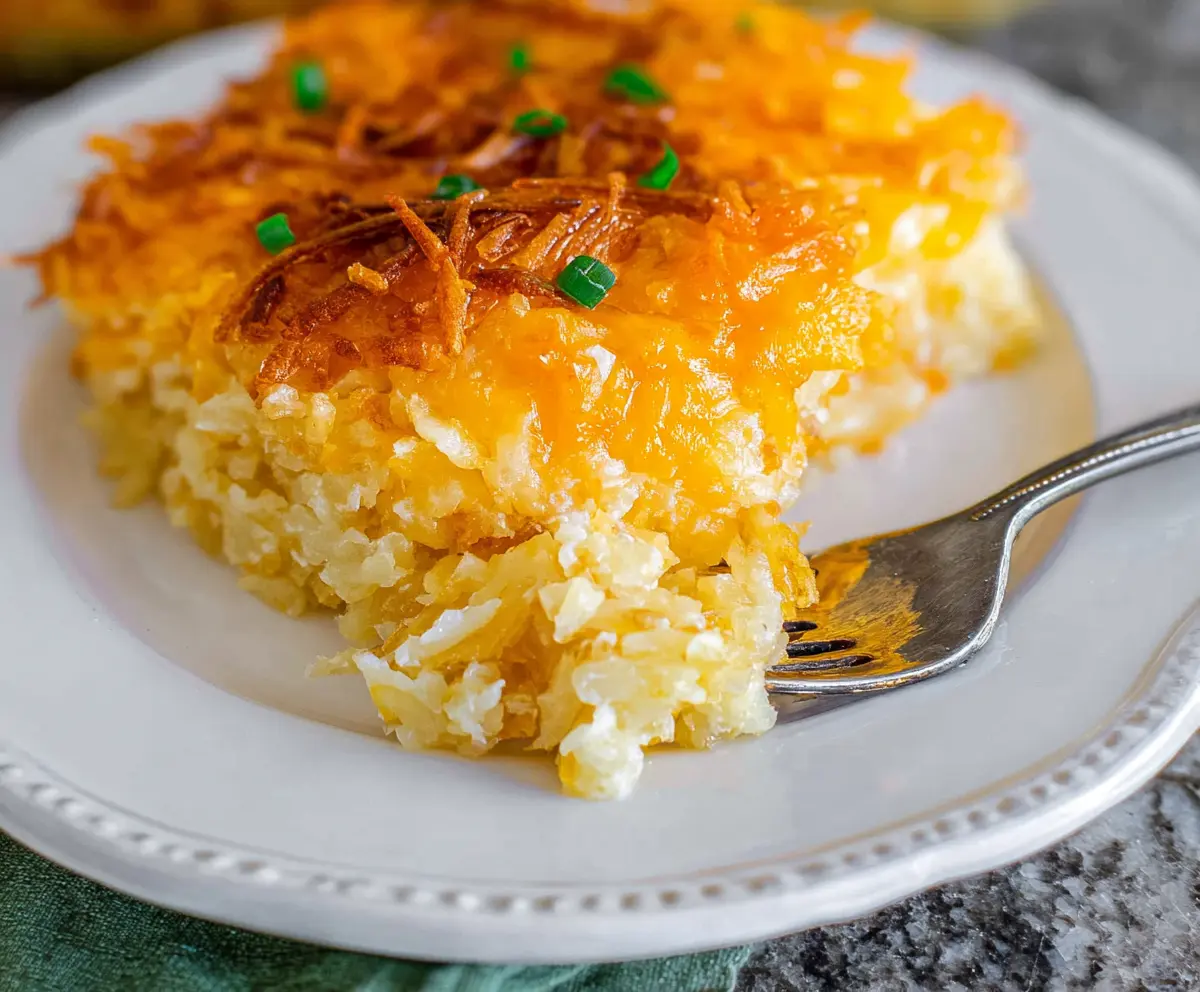Delicious cheesy hashbrown potato casserole topped with melted cheese and crispy edges.