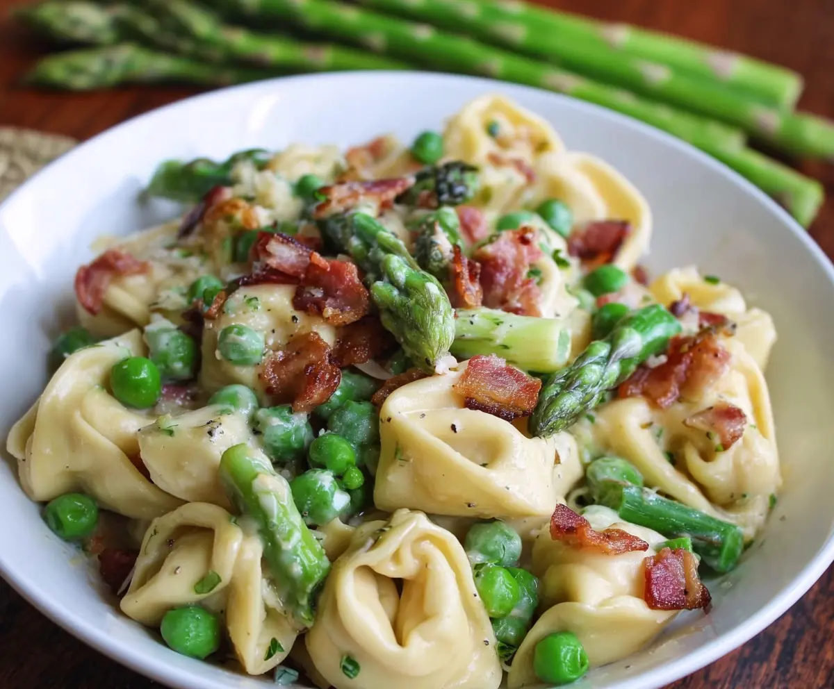 Delicious tortellini pasta with peas, asparagus, and crispy bacon on a plate.